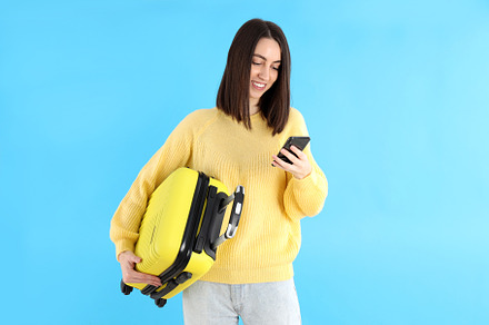 Attractive woman with phone and travel bag on blue background, a Person Photo by AtlasStudio PRO