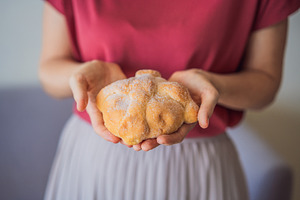 Woman presenting pan de muerto, a Person Photo by Elizaveta Galitskaya