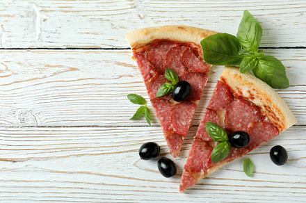 Slices of Salami pizza on white wooden background, a Food & Drink Photo by AtlasStudio PRO