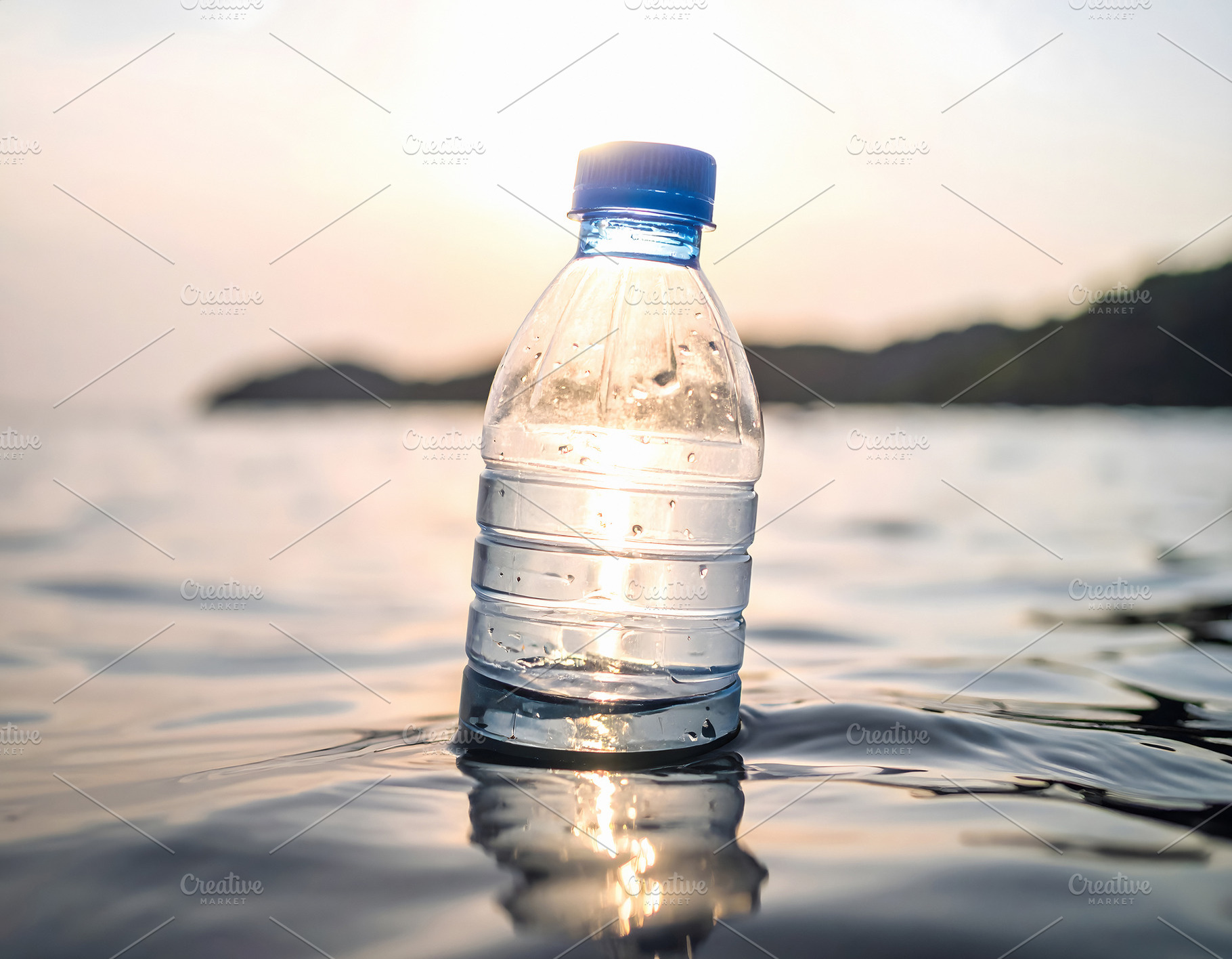 Plastic bottle floating in ocean water at sunset, a Nature Photo by GoodGoods
