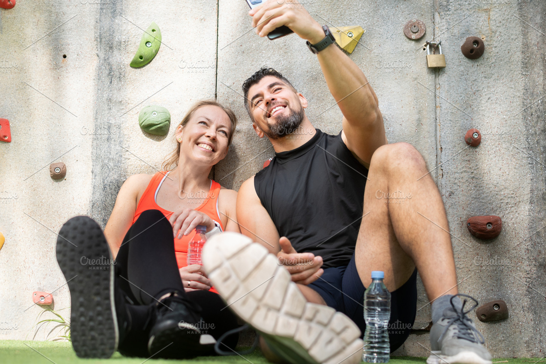 Happy fitness couple taking selfie after workout near outdoor climbing wall, a Food & Drink Photo by etorres69