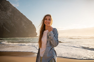 Happy woman in denim shirt standing on seashore against sky at beach, a Person Photo by andreonegin market