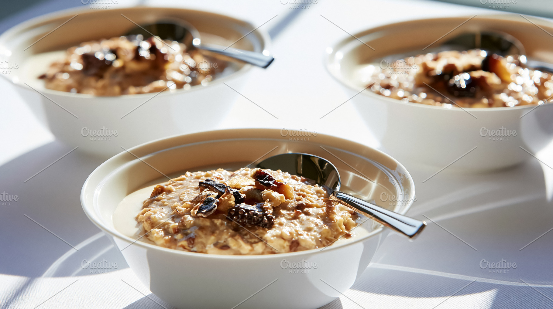 Oat porridge bowls topped with dried fruit and nuts, offering a nutritious and, a Photo by Studio ANNA