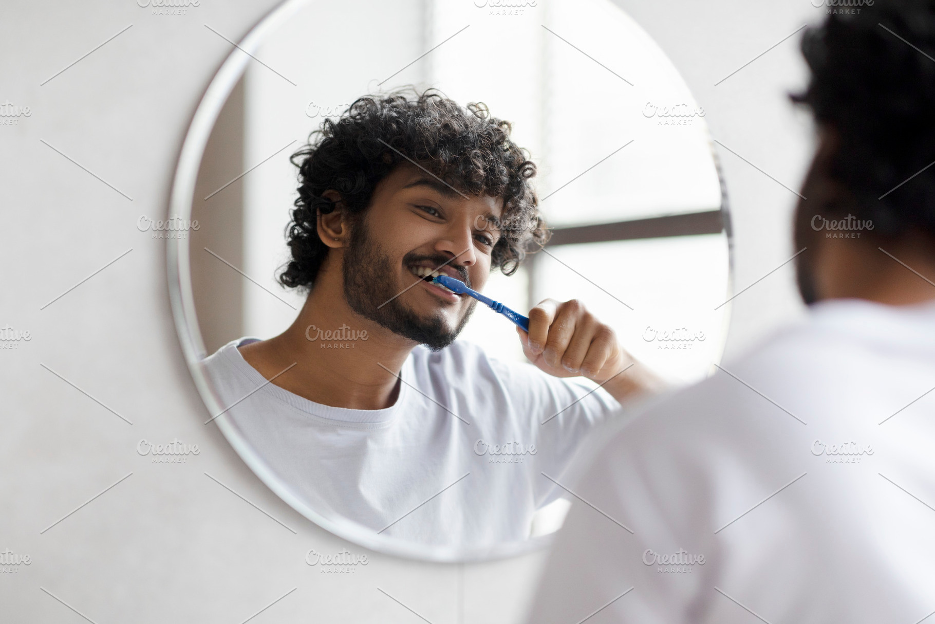 Dental care. Happy indian man brushing his teeth with toothbrush in bathroom, s, a Person Photo by Prostock-Studio