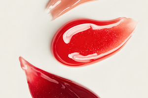 Three glossy lip gloss swatches in shades of nude, red, and berr, a Photo by Studio ANNA