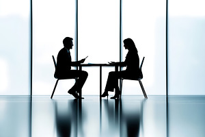Two business professionals engaged in a discussion at a modern office table dur, a Photo by AlyaAnd