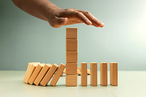 Hand stopping falling dominoes, Economic crisis prevention, a Photo by salmon.black
