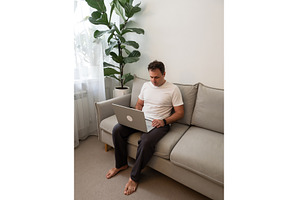 Man using laptop on gray sofa, a Technology Photo by Fascinadora