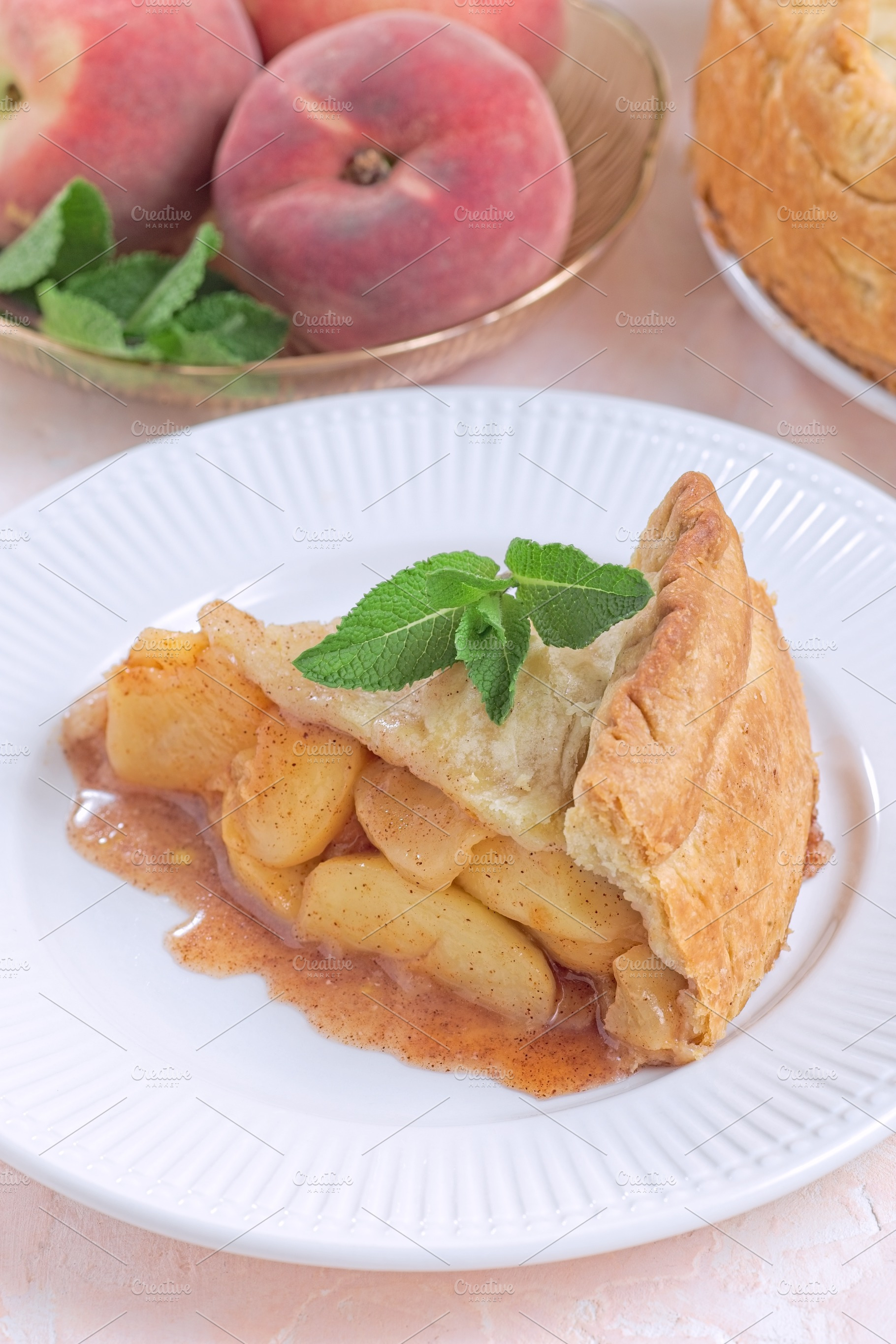 Old fashioned deep dish peach pie slice garnished with fresh mint, on white pla, a Food & Drink Photo by iuliia_n