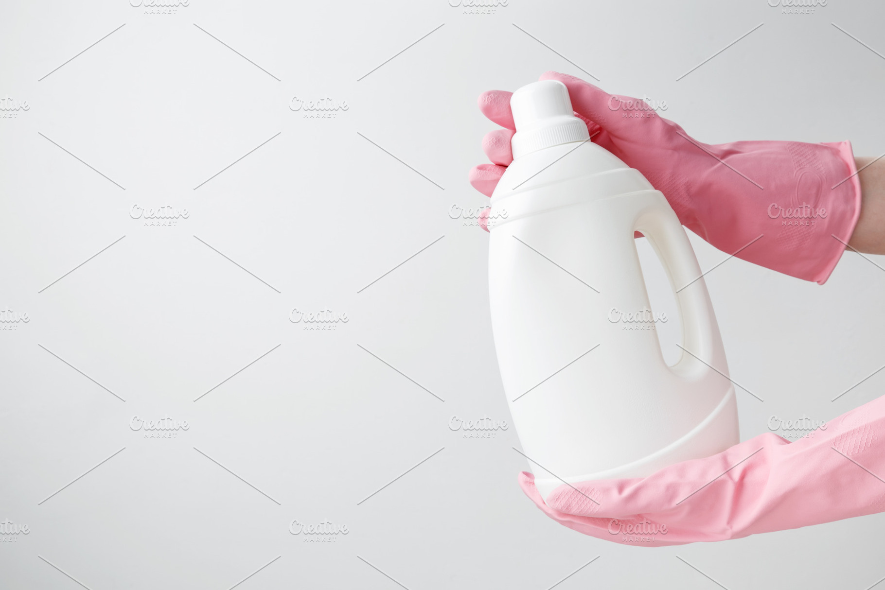 Female hand in a pink rubber glove holding a white branding mockup of laundry g, a Photo by matucha