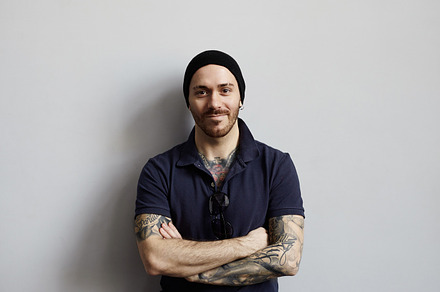 Attractive athletic man with muscular and tattooed hands on neutral grey background. Happy guy look to the camera. Cool driver studio portrait., a Person Photo by Anatoliy Karlyuk