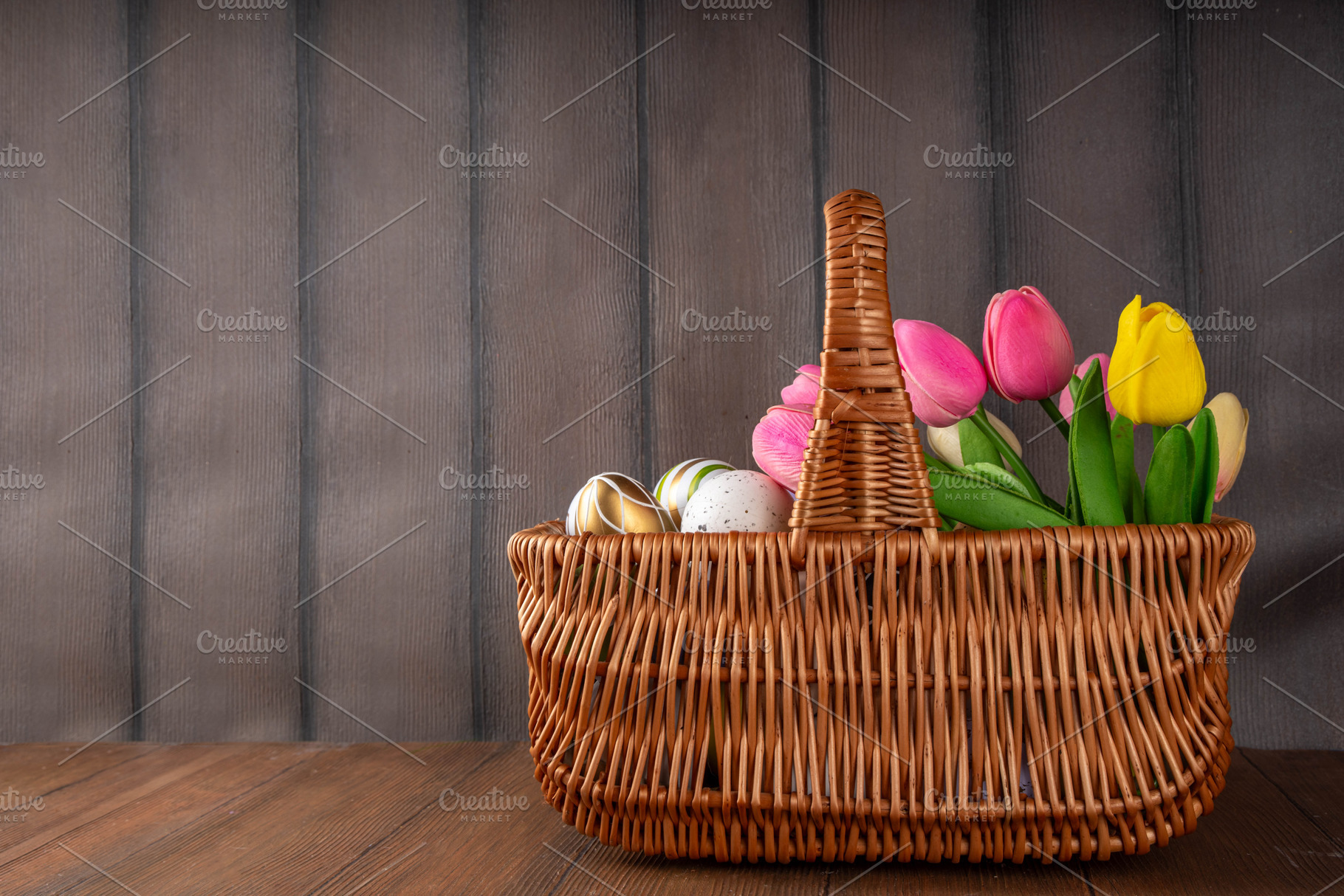 Easter eggs and tulips flowers in basket on wooden background, a Holiday Photo by Rimma