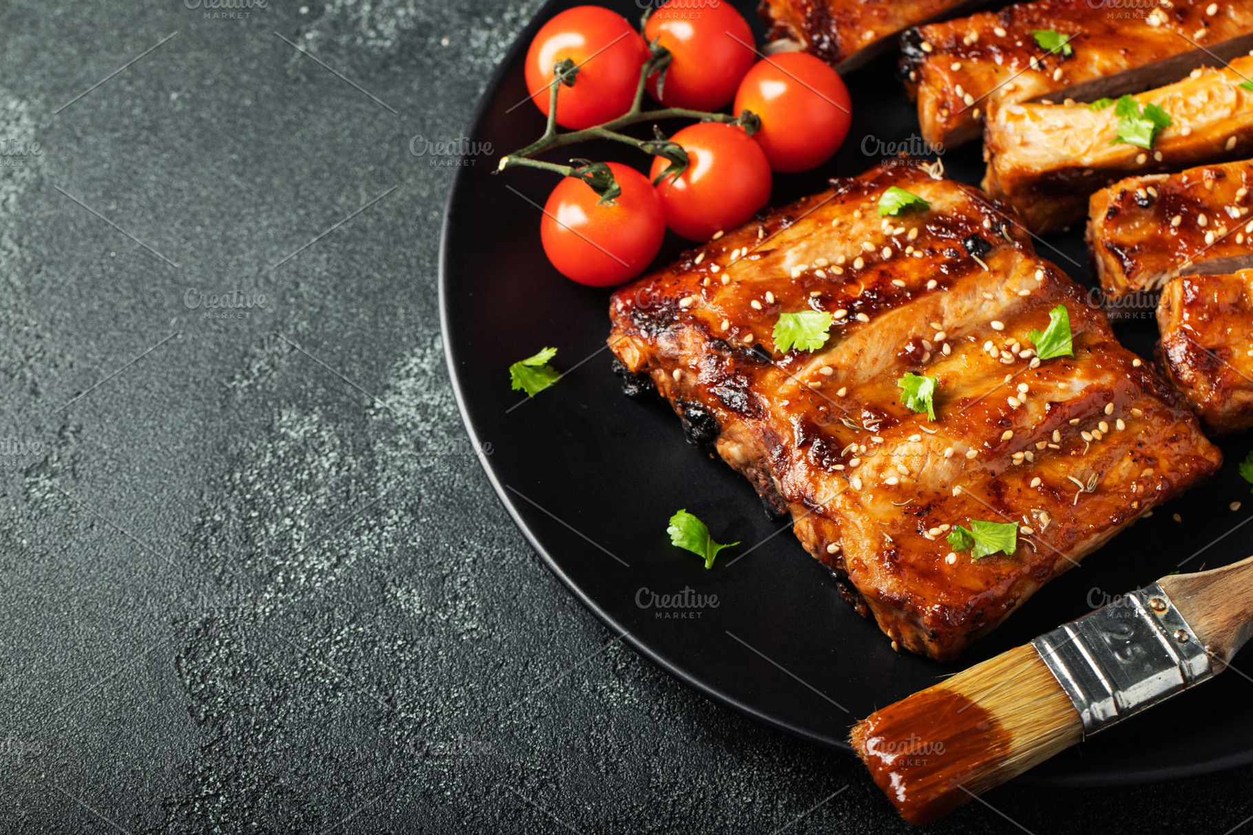 Hot grilled spare ribs from a summer BBQ served on a plate with sauce. Top view, a Food & Drink Photo by Budarinphoto