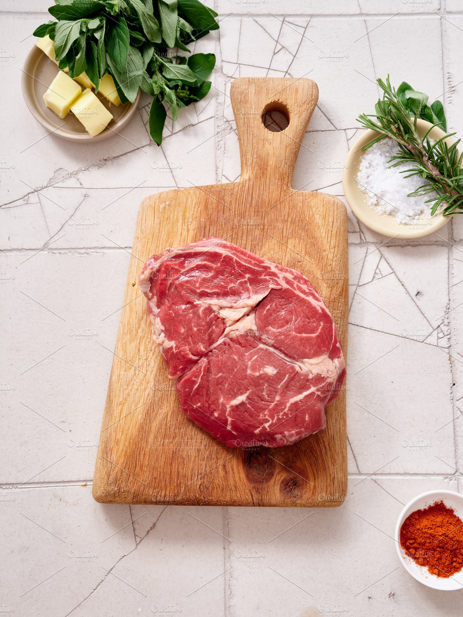 Raw rib-eye steak on wooden cutting board with spices and herbs ready for cooki, a Food & Drink Photo by Asya Nurullina