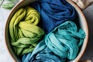 Colorful fabrics in a bowl with green leaves, an Abstract Photo by AlyaAnd