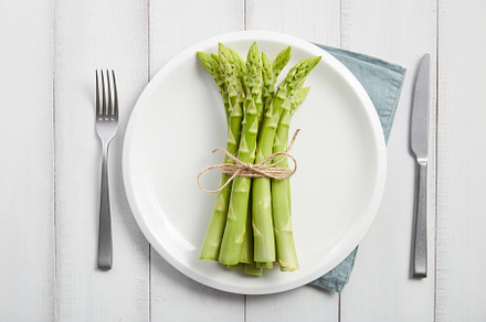 Bunch of fresh asparagus on white plate