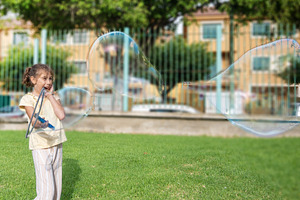 Young girl playing with giant soap bubbles outdoors, a Person Photo by etorres69