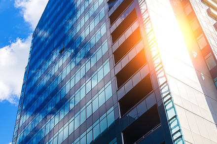 blue glass modern business center in summer with sun behind, a Business Photo by VLADIMIRCARIBB