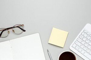 Organized workspace featuring keyboard, glasses, notebook, and stationery suppo