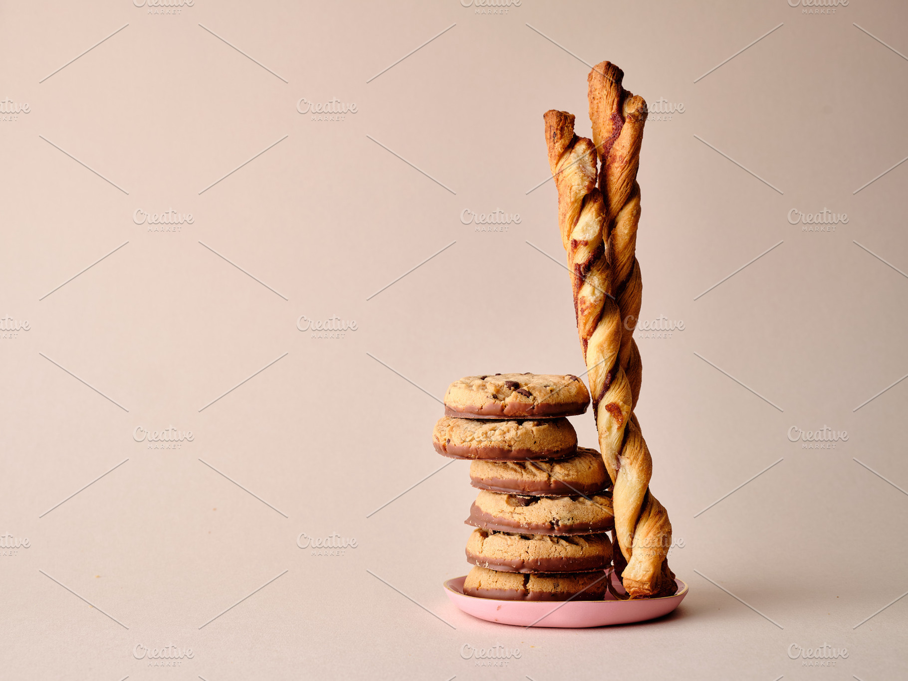 A stack of chocolate-covered biscuits and cookie sticks on beige, a Photo by Asya Nurullina