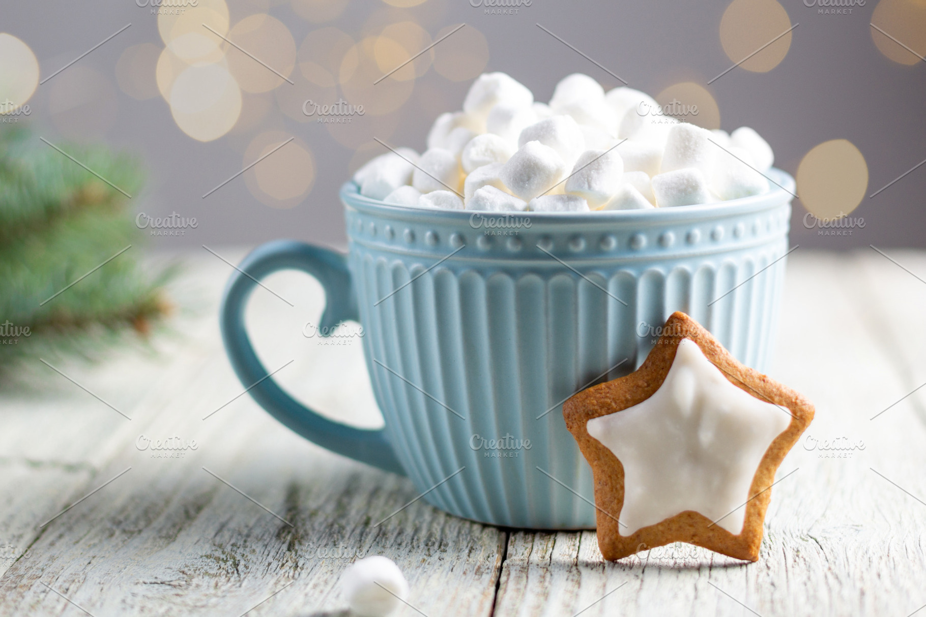 A blue cup of winter hot drink with marshmallows and gingerbread star on a whit, a Holiday Photo by dashtik