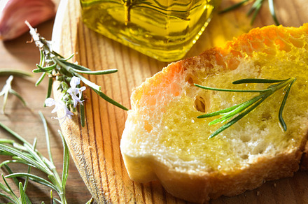 Slice of bread seasoned with rosemary-essenced oil on wooden pla, a Food & Drink Photo by Davizro's Market