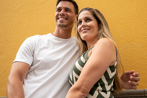 Happy couple holding hands against colorful yellow wall, a Food & Drink Photo by etorres69
