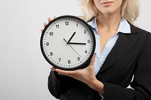 Deadline and punctuality. Unrecognizable young businesswoman holding clock, sta, a Photo by Prostock-Studio