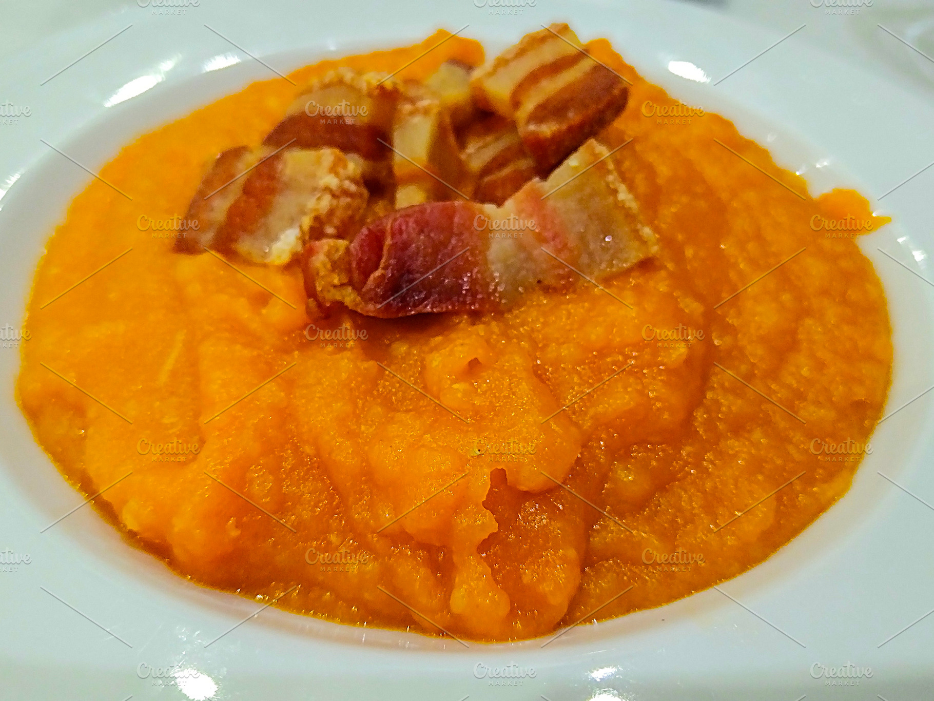 Mashed pumpkin with crispy bacon on white plate, a Food & Drink Photo by DanFLCreativo