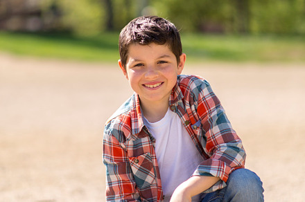 Young boy squatting on a gravel path in a sunny park., a Person Photo by RF Images