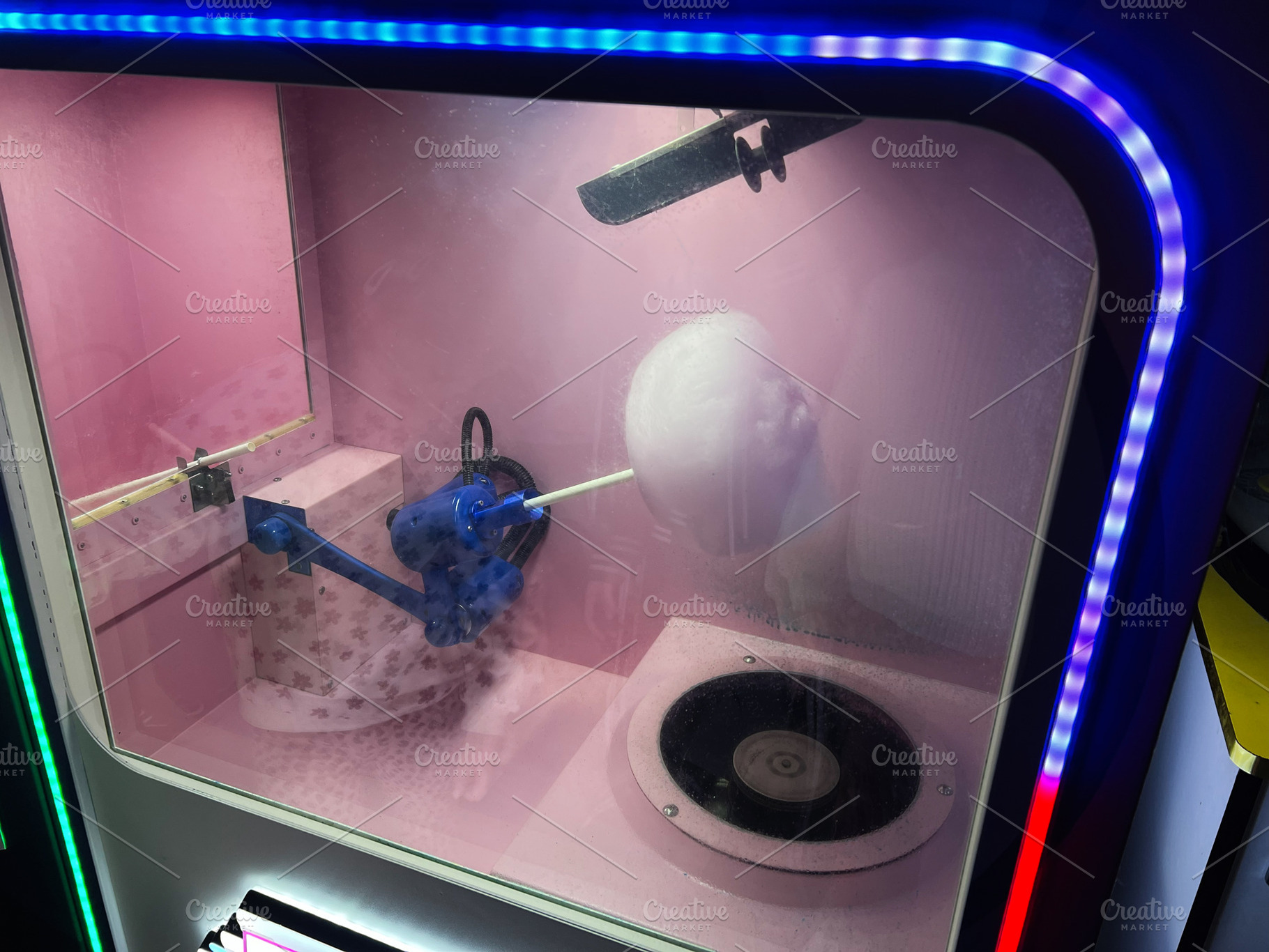 Cotton candy machine with colorful display and twirling sugar on a stick, a Photo by AS photostudio