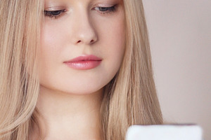 Young blonde woman using smartphone, browsing social media or texting with digi, a Person Photo by Studio ANNA