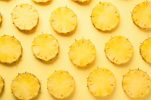 Ripe sliced pineapples on yellow background, a Food & Drink Photo by AlyaAnd