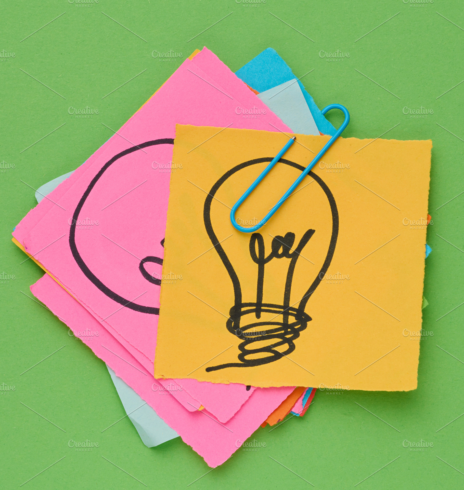Stack of sticky notes with a light bulb drawn on them is held to, a Business Photo by ndanko