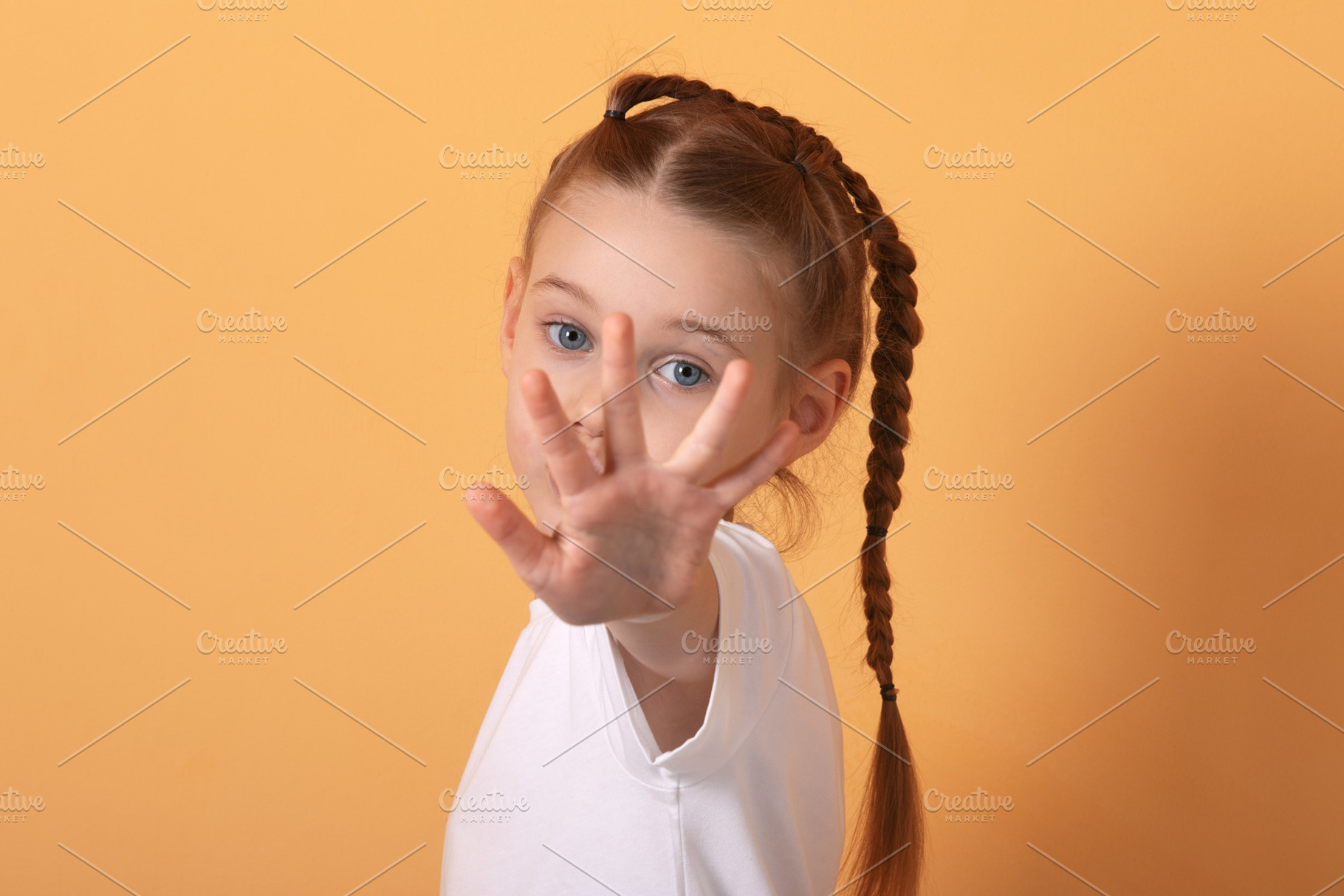 Portrait of a young girl with braids playfully extending her han, a Person Photo by Ales Munt