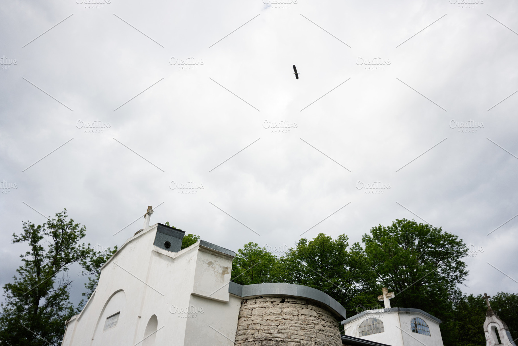 Scenic View of Columbarium and Bird Flying Under Cloudy Skies, a Photo by AS photostudio