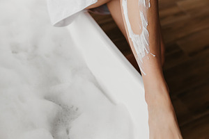 Young woman shaving legs using safety razor, removing hair, making depilation i, a Photo by Prostock-Studio