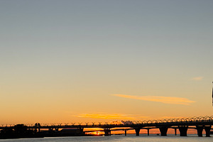 A serene sunset over a calm river, with a bridge silhouetted against the colorf, a Nature Photo by Textures & Backgrounds