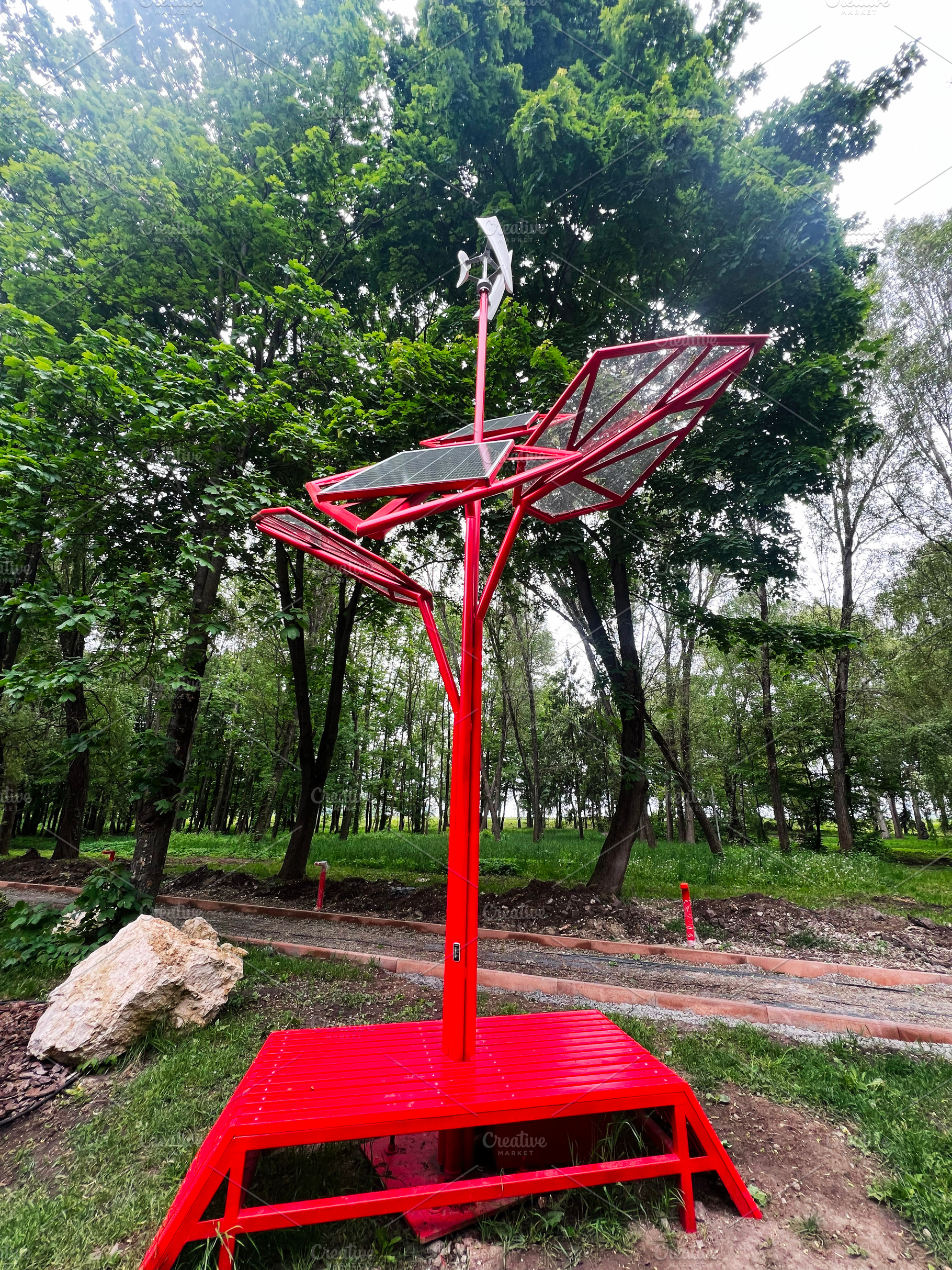 Red solar powered charging station in a park surrounded by greenery, a Photo by AS photostudio