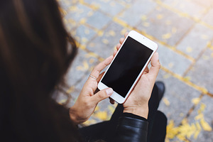 Hands holding white mobile phone wit