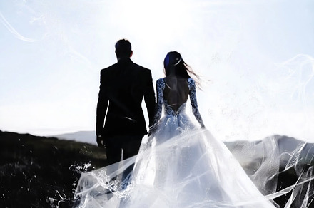 A couple holding hands, silhouetted against a bright sky. The woman wears a flo, an Arts & Entertainment Photo by Textures & Backgrounds