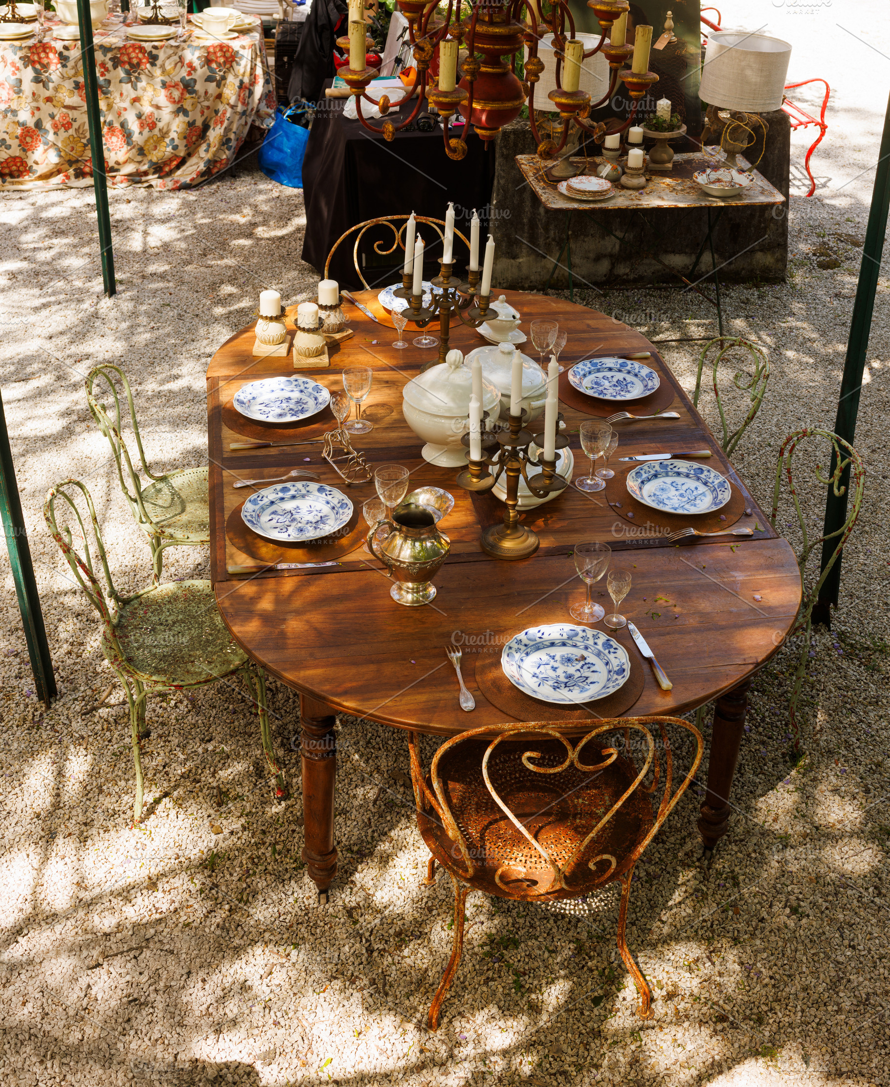 Wooden outdoor table in a garden courtyard set with vintage plat, a Food & Drink Photo by Bepslabor
