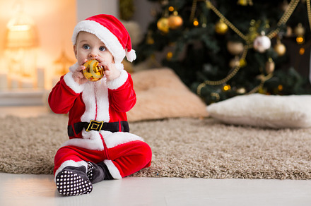 Funny baby boy weared in santa hat with golden christmas ball featuring
