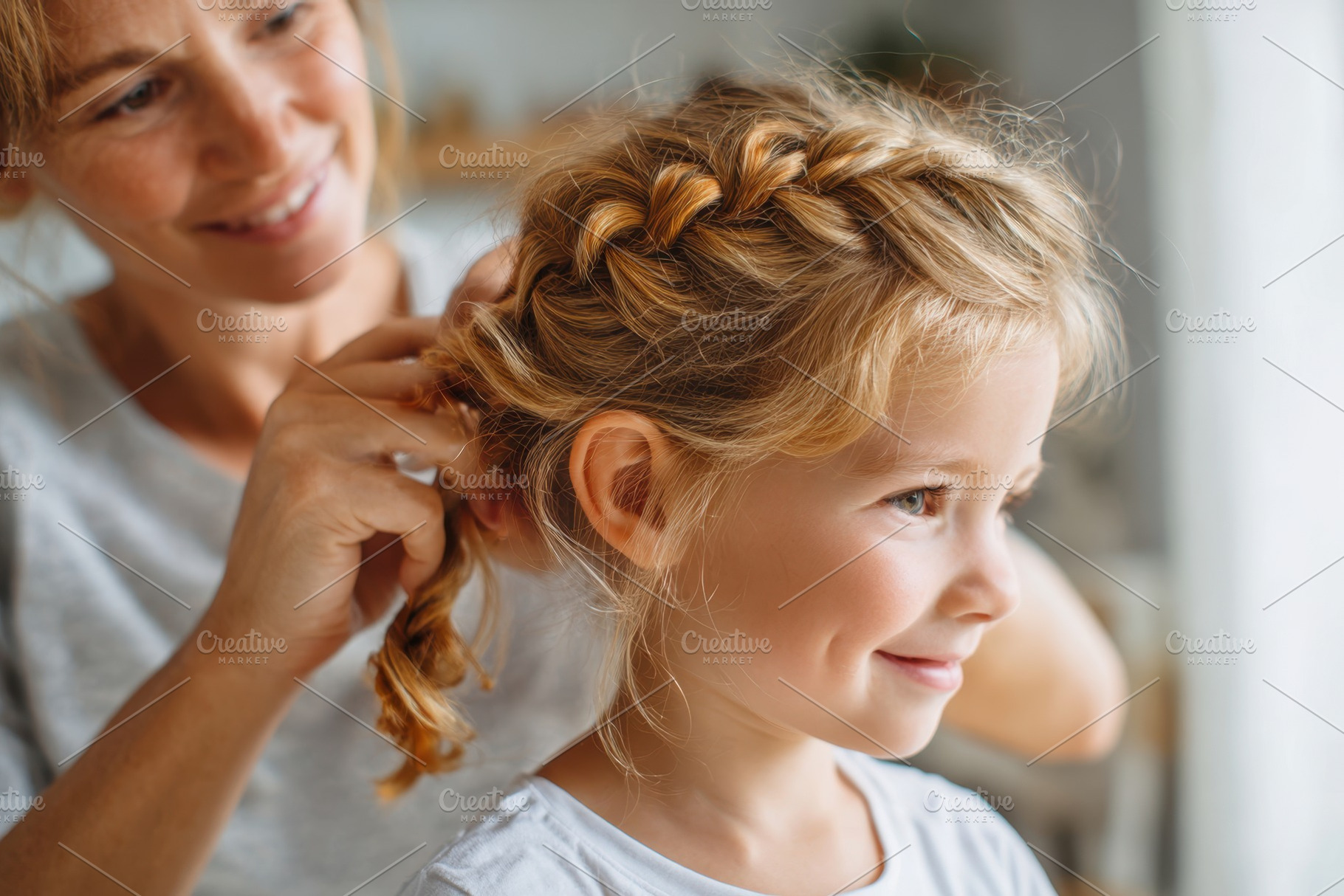 Mother braiding daughter's hair in cozy home setting, a Person Photo by AlyaAnd