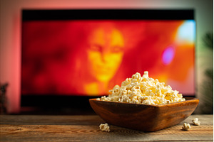 A wooden bowl of popcorn and remote, a Technology Photo by Budarinphoto