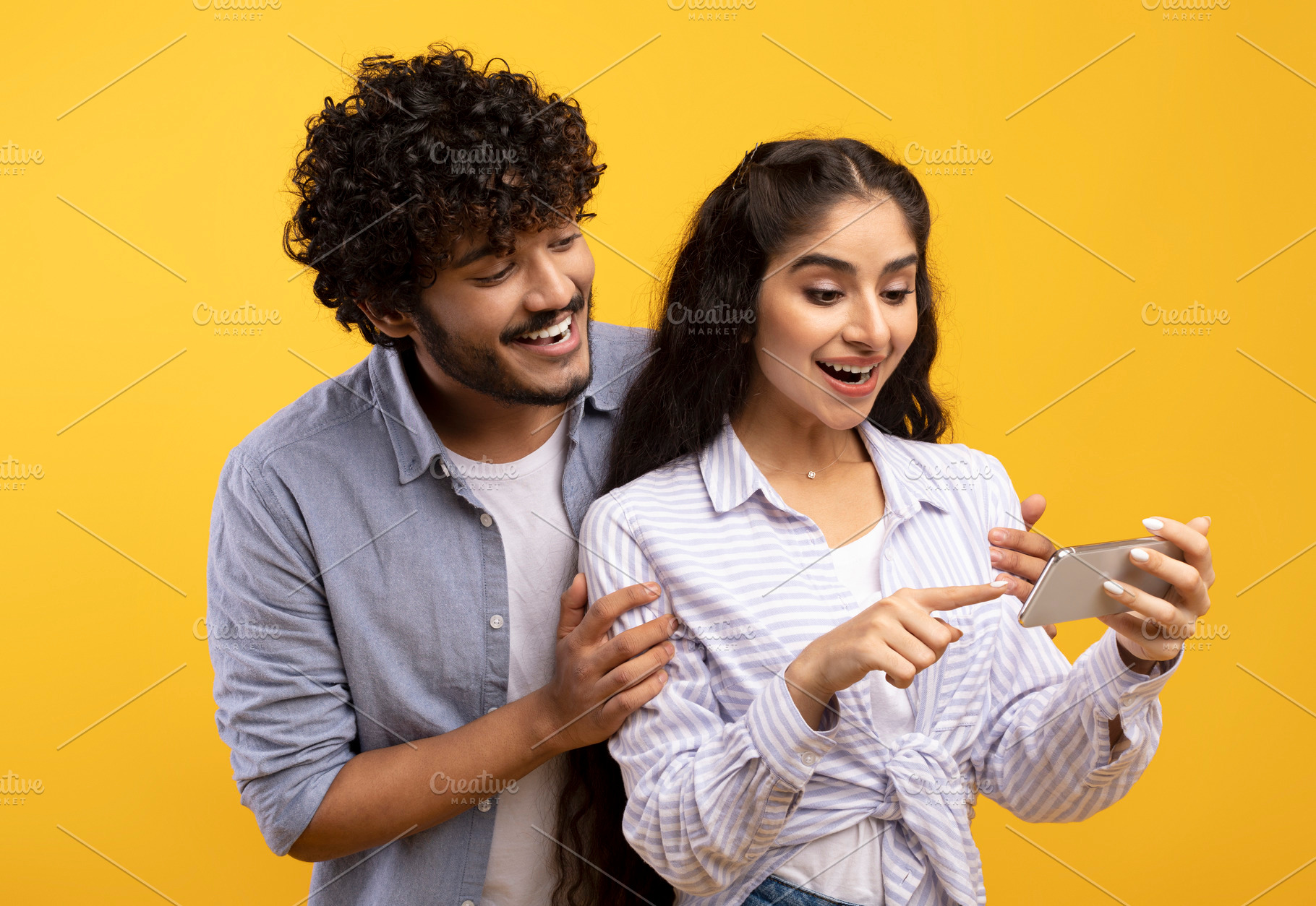 Excited indian couple looking at smartphone screen, using new app or reading co, a Photo by Prostock-Studio