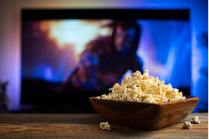 A wooden bowl of popcorn and remote, a Technology Photo by Budarinphoto