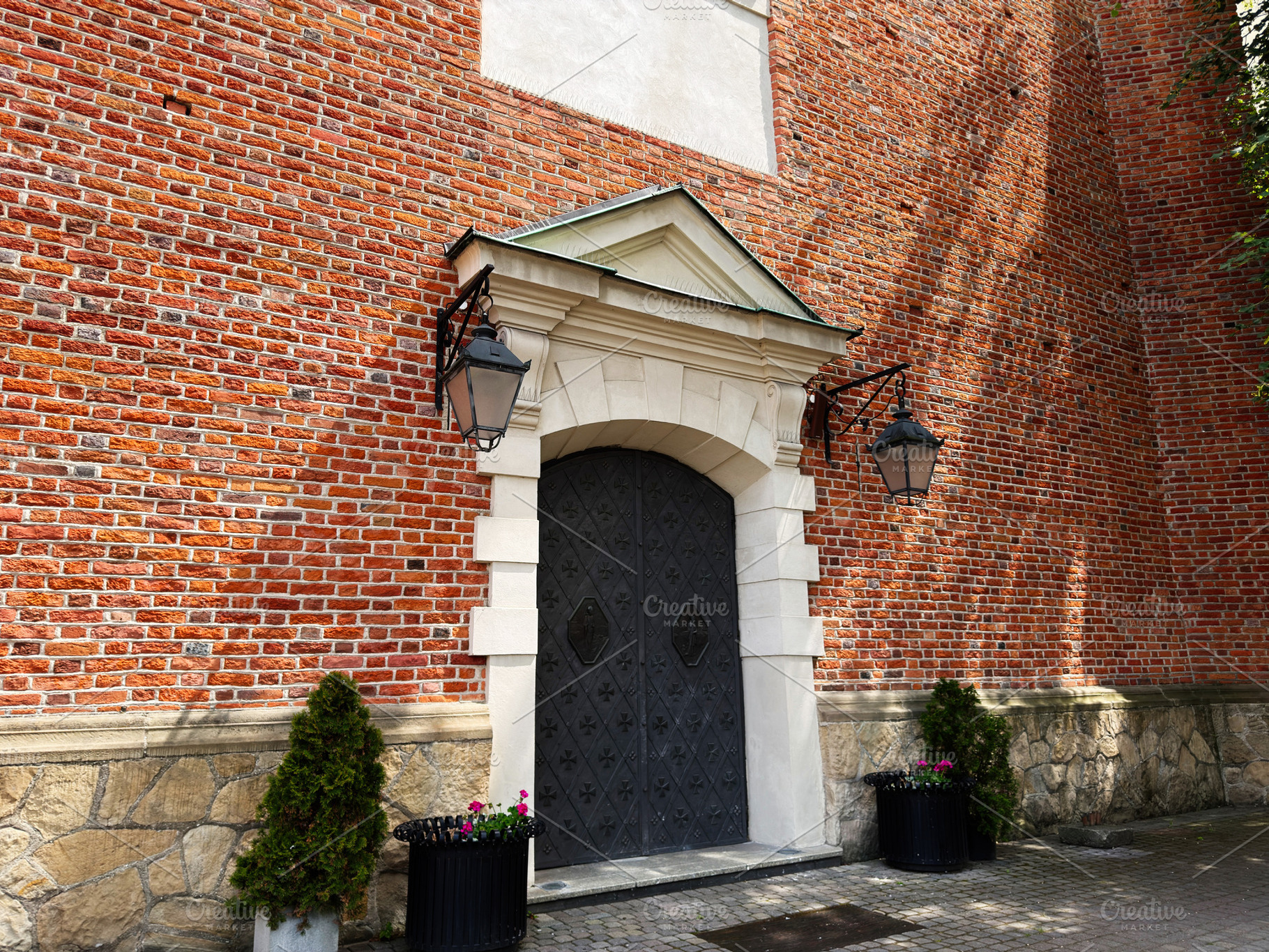 Ornate metal door and brick entrance with lanterns and planters, a Photo by AS photostudio