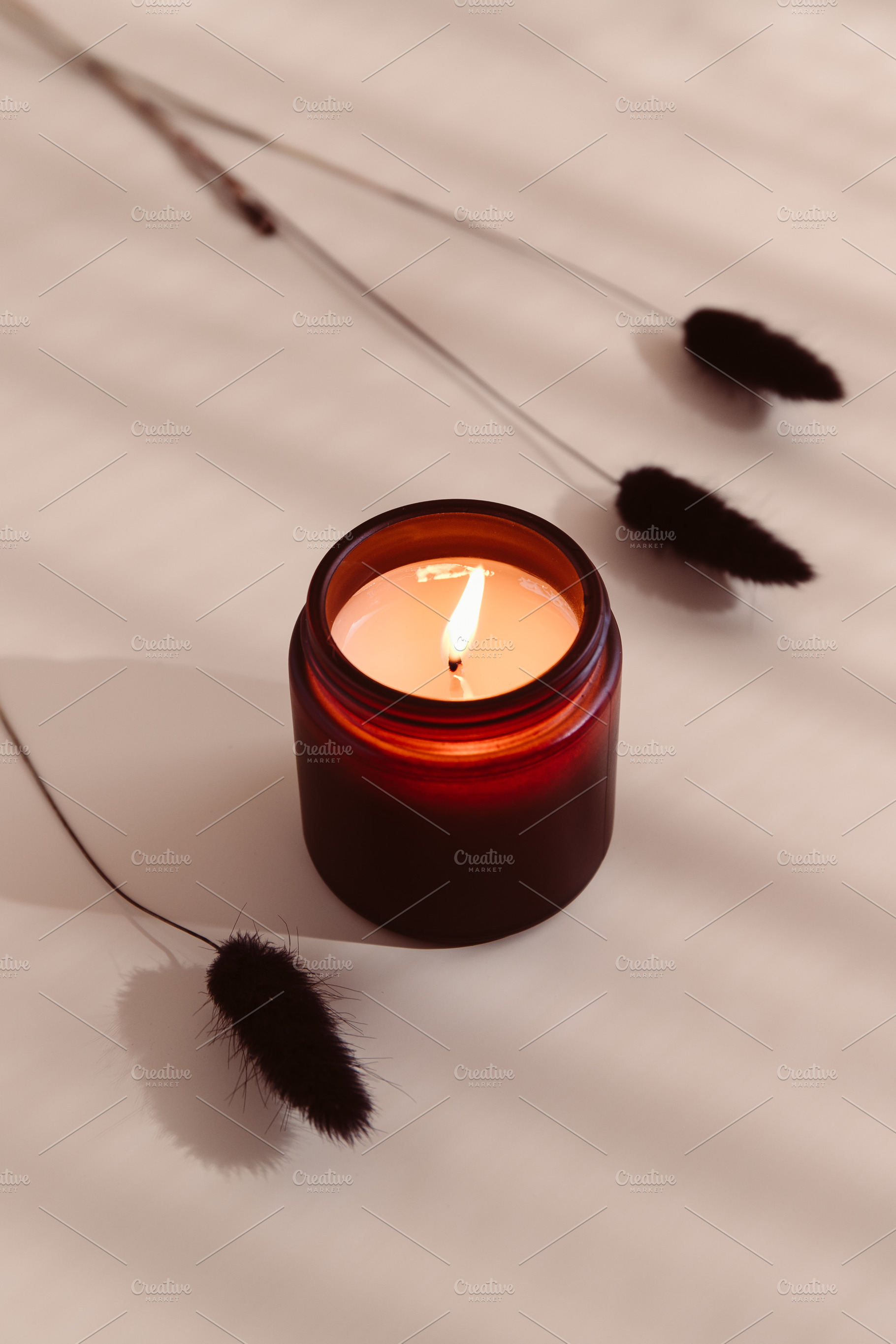 Burning candle in a dark amber glass, a Photo by Edalin's Store
