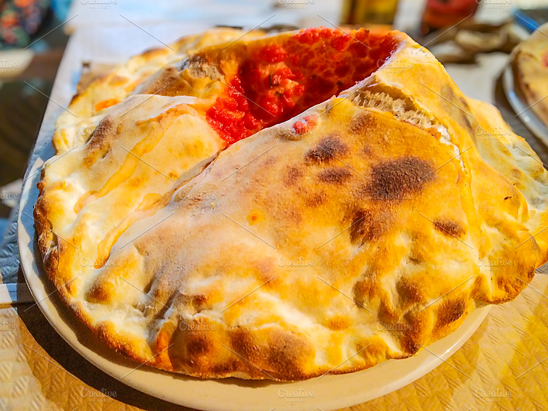Folded pizza calzone served at restaurant table, a Food & Drink Photo by DanFLCreativo
